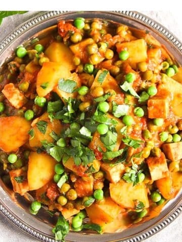 vegan tofu potato curry sprinkled with peas and parsley overhead picture