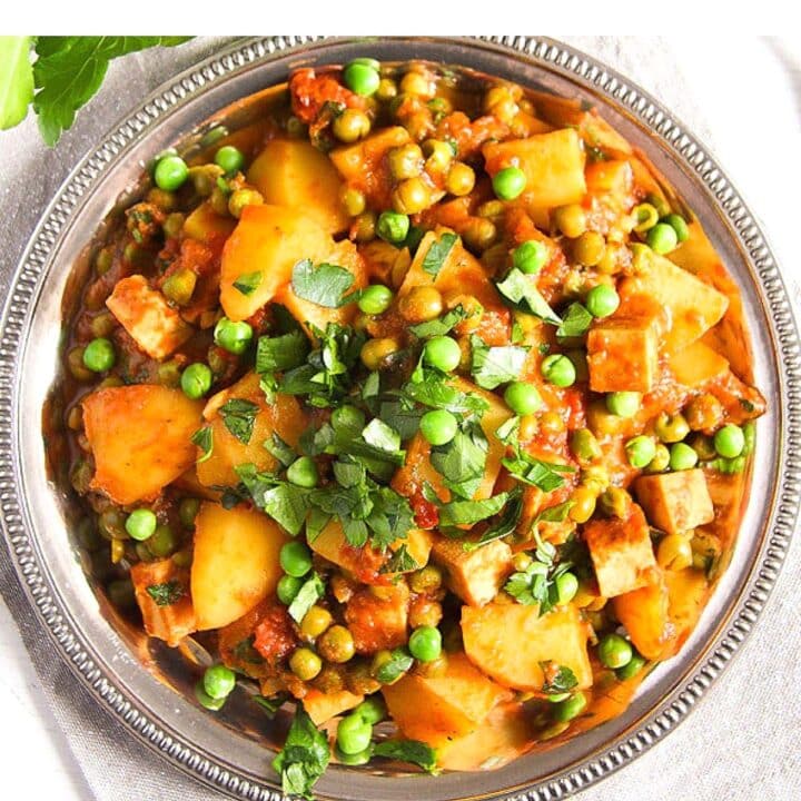 vegan tofu potato curry sprinkled with peas and parsley overhead picture