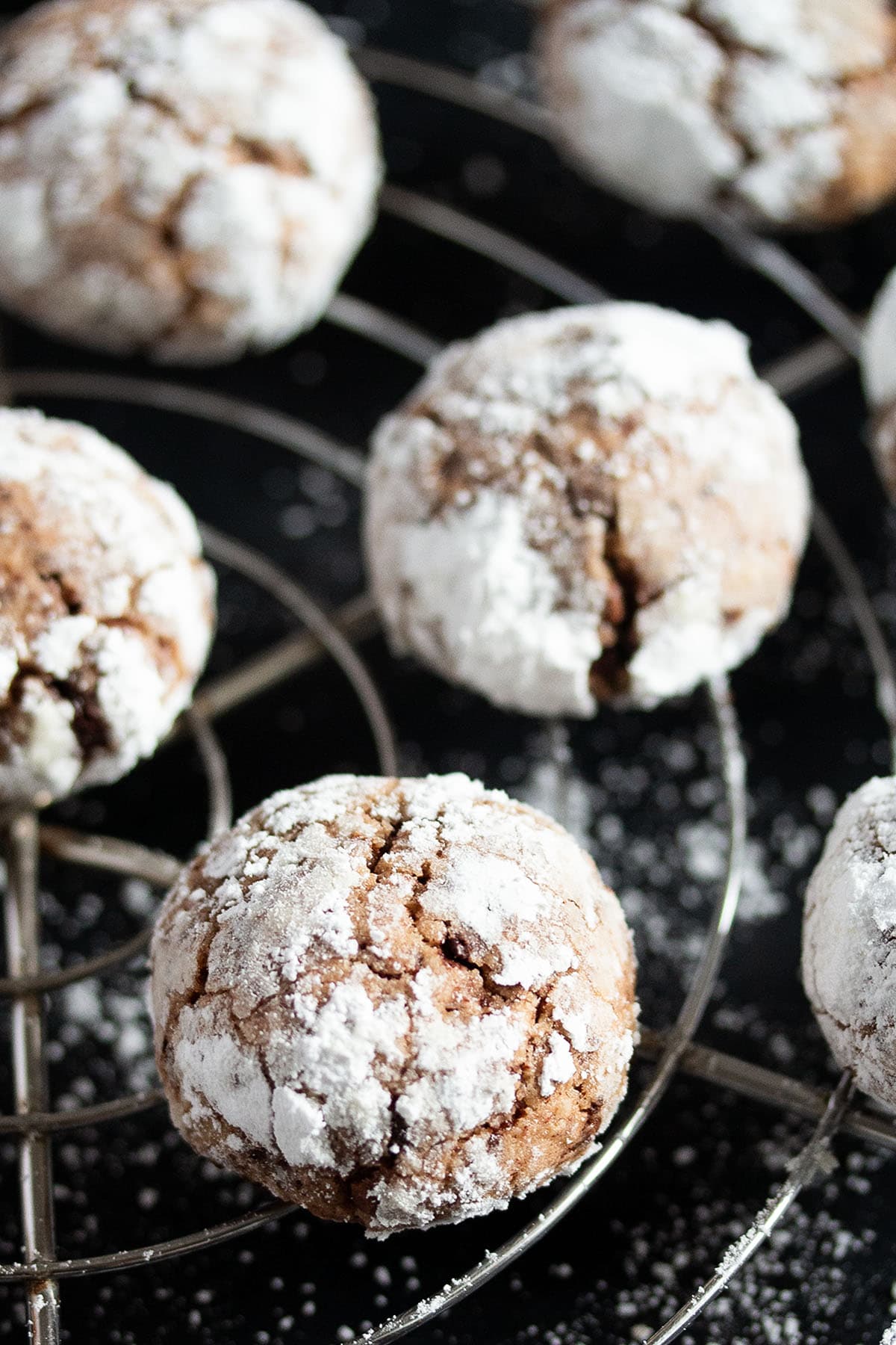 many chocolate almond cookies dusted with icing sugar on a wire rack.