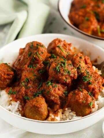 curried turkey meatballs heaped on a bed of rice in a bowl.