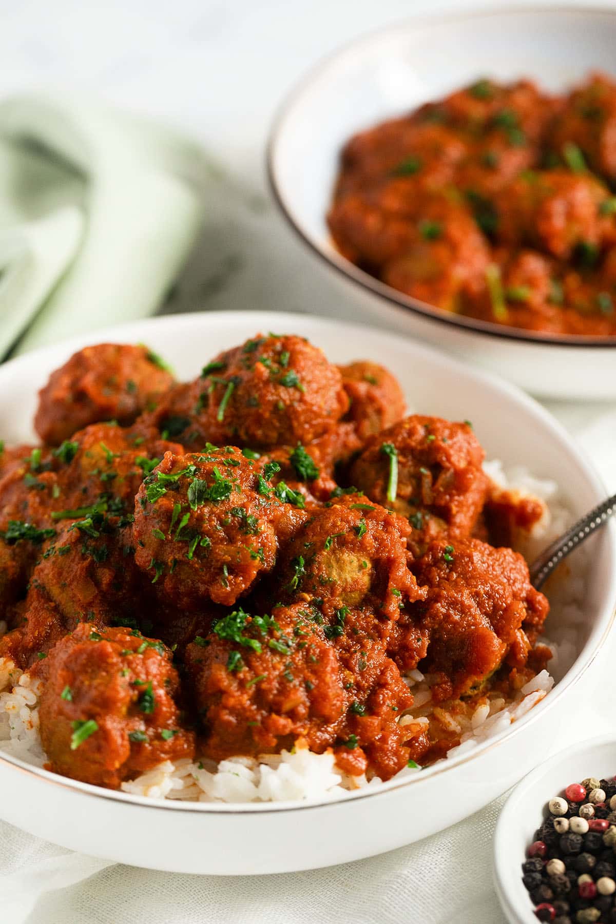 turkey meatballs with curry sauce on rice and another bowl of meatballs behind.