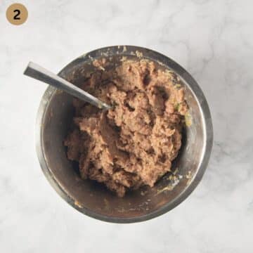 mixture for making turkey meatballs for curry in a bowl with a spoon in it.