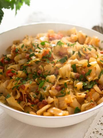 fried cabbage with bacon in a small white bowl.