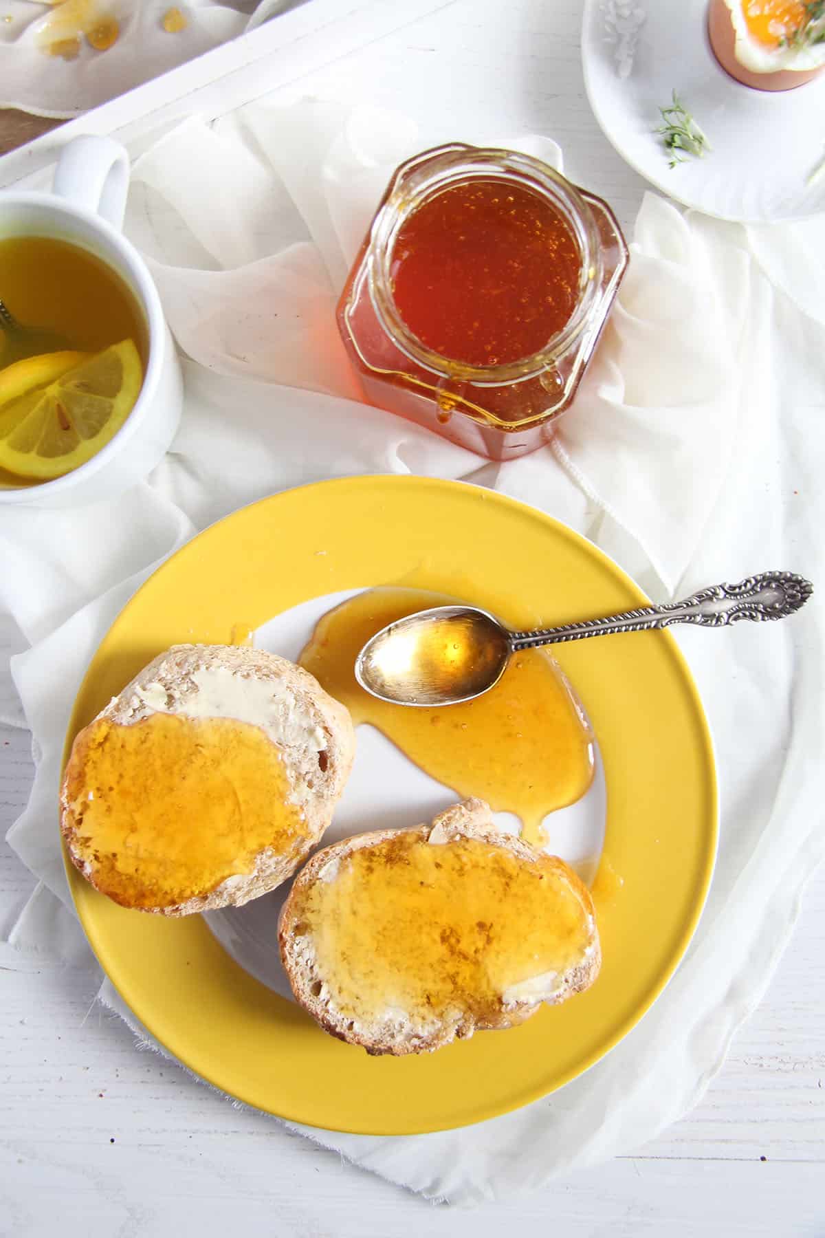 bread rolls with butter and lemon jelly on a yellow plate.