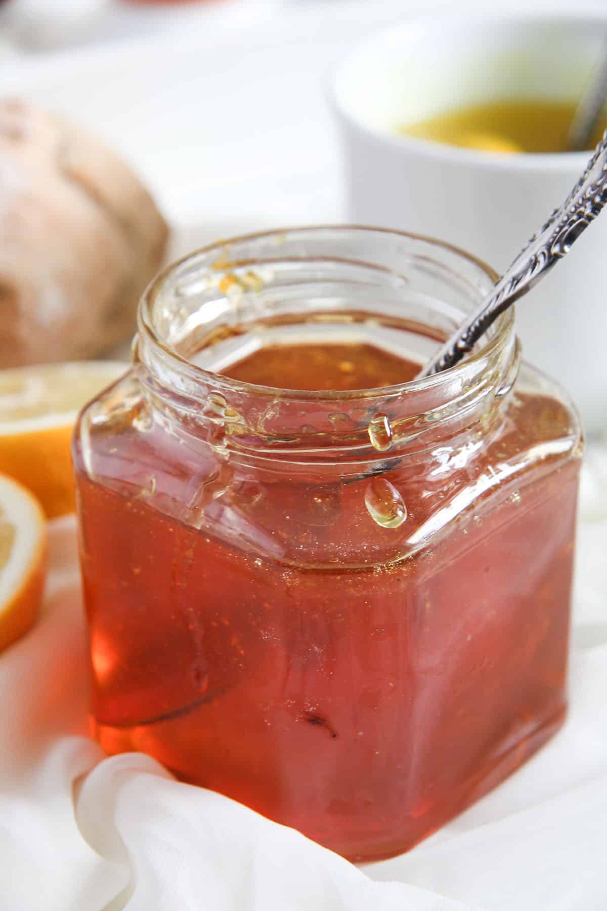 jar full of golden lemon jelly with a spoon in it.