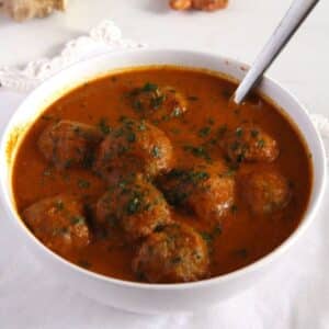 spicy turkey meatball curry in a white bowl with a spoon in it.