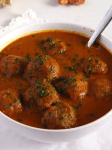 spicy turkey meatball curry in a white bowl with a spoon in it.