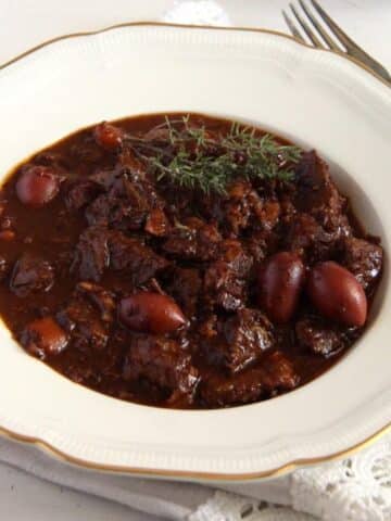 french beef stew with olives in a vintage deep plate.