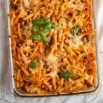 bolognese pasta bake garnished with fresh basil in a baking dish.
