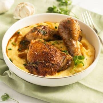 chicken and polenta sprinkled with parsley in a bowl.
