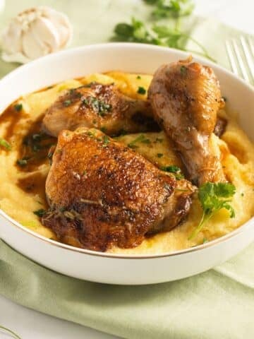 chicken and polenta sprinkled with parsley in a bowl.