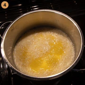 adding polenta to water in a pot on the stove.