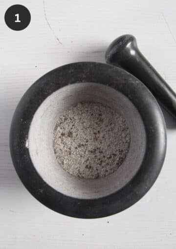 crushed salt and spices in a mortar with a pestle beside it.