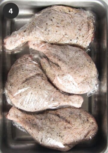 four raw duck legs wrapped in cling film for marinating.