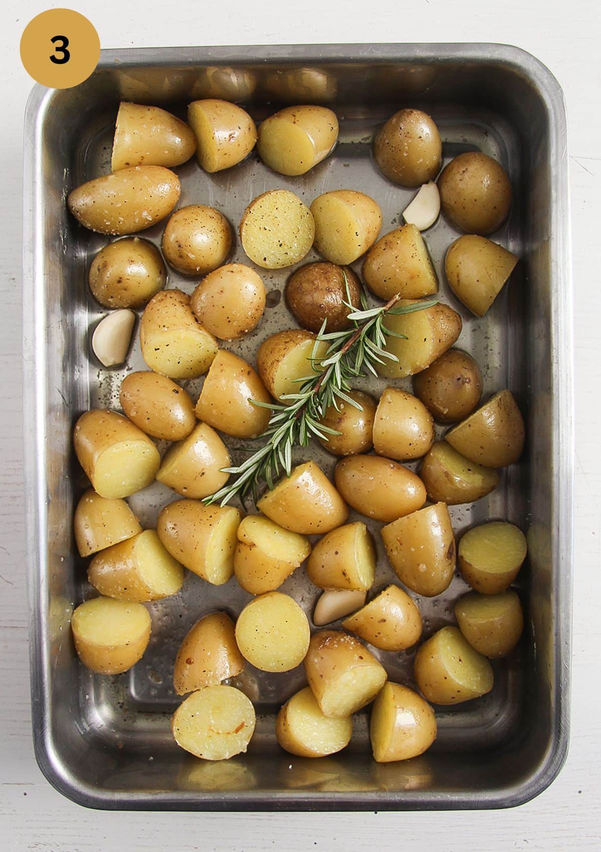 raw halved potatoes tossed in melted duck fat in a roasting tin before cooking.