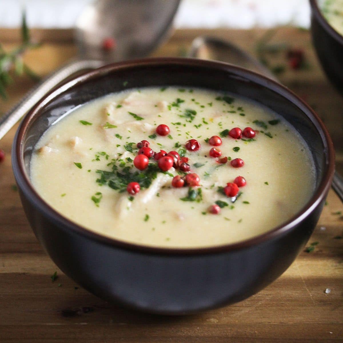 cream of turkey soup garnished with red peppercorns in a small brown bowl.