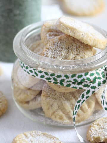 eggless almond cookies in a small mason jar with a ribbon around it.