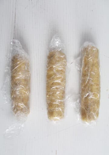 three logs of cookie dough wrapped in cling film.