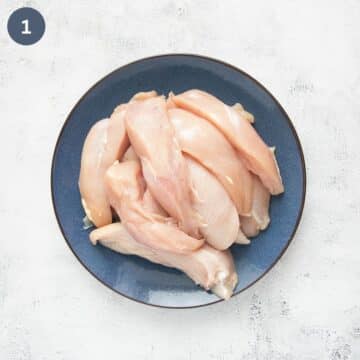 raw, halved chicken breast pieces on a large plate.
