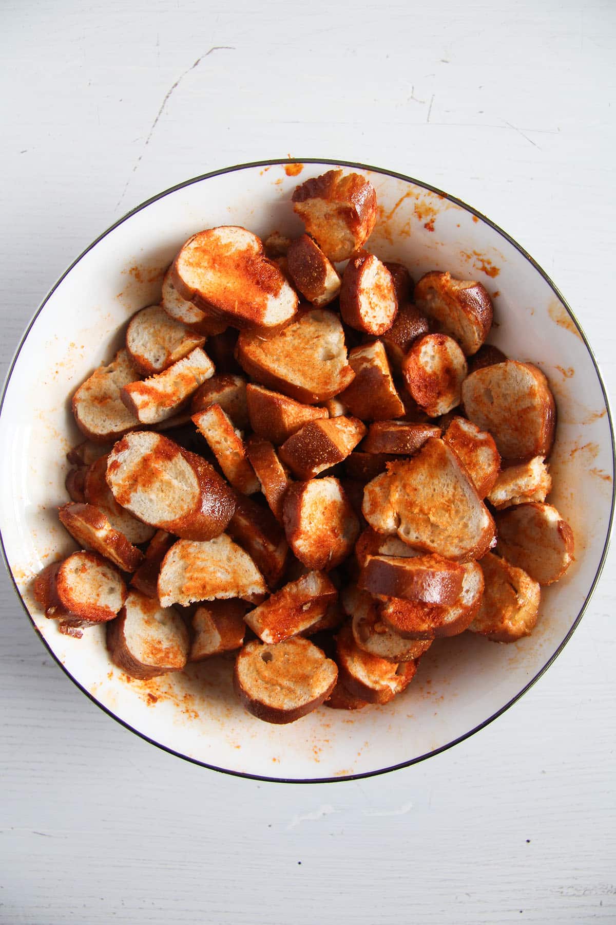 pretzel pieces rubbed with oil and spices in a bowl before baking.