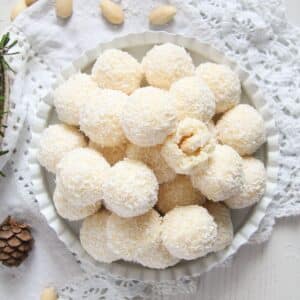 raffaello balls on a small white plate with almonds around it.