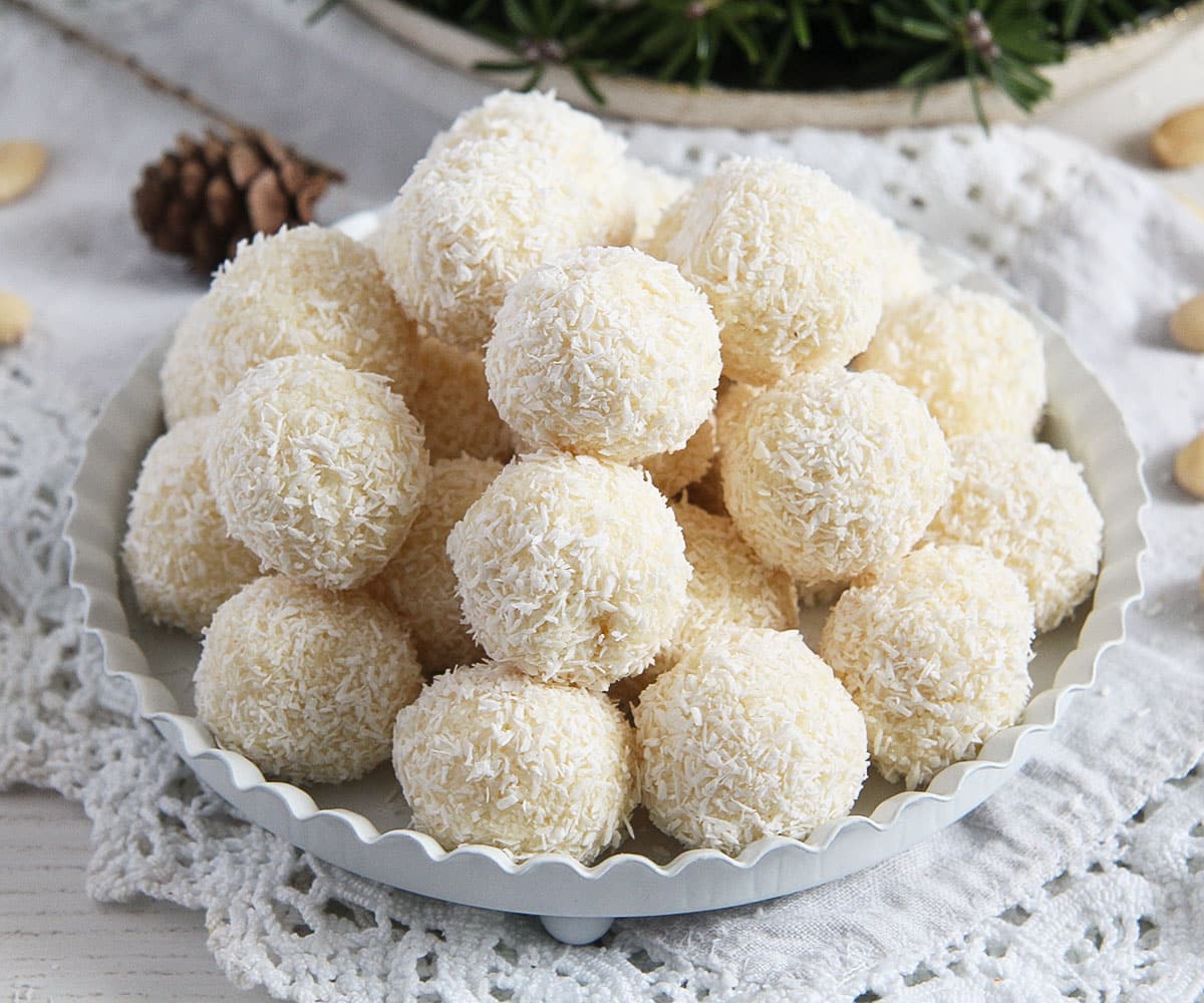 many stapled homemade raffaello coconut balls on a small white serving plate.