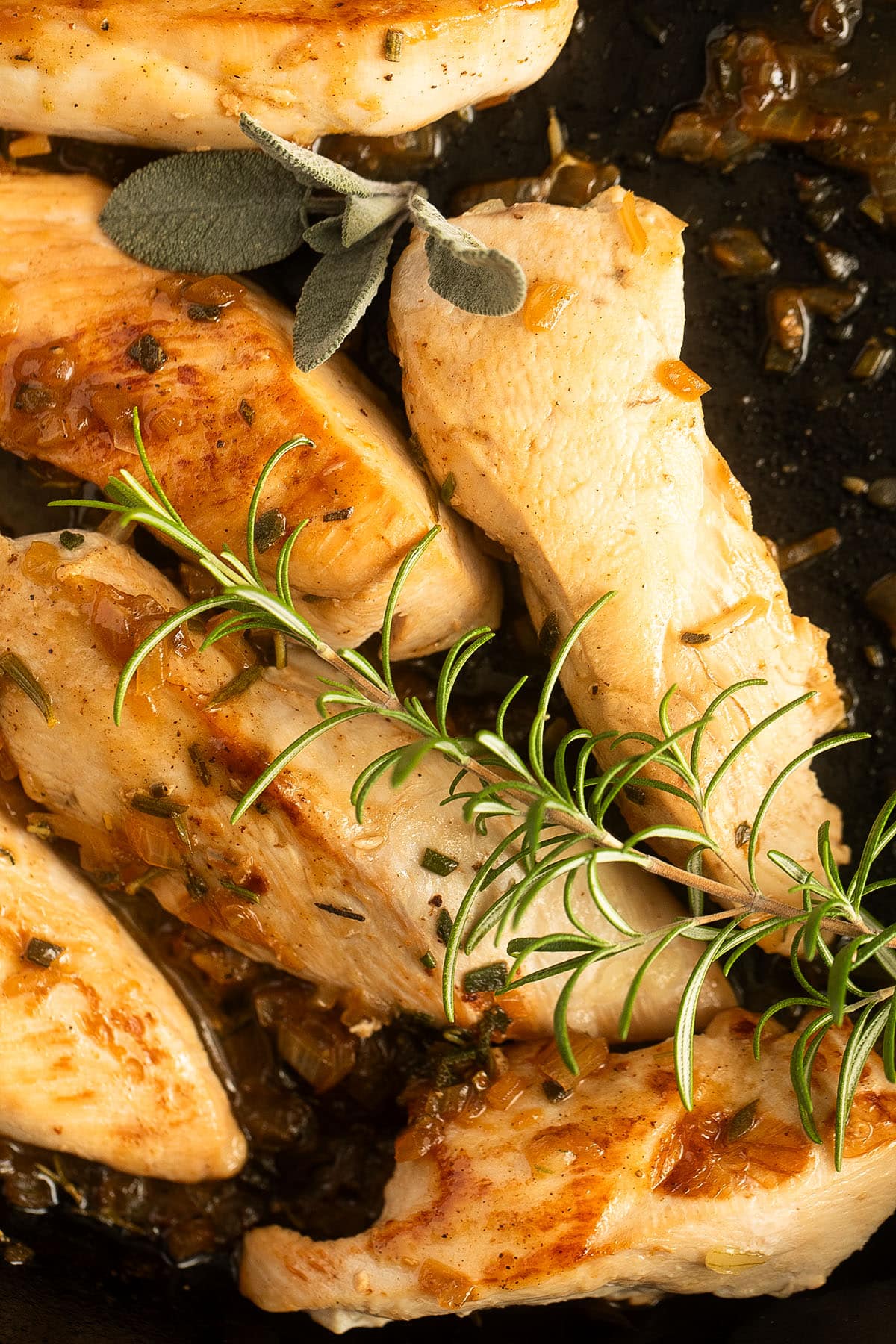 golden brown chicken breast pieces with a sprig of rosemary on top.