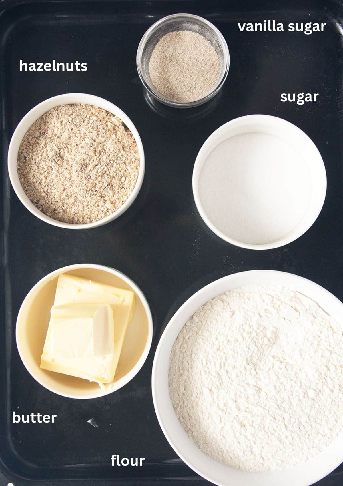 labeled ingredients for making vanillekipferl: ground hazelnuts, vanilla sugar, butter, sugar, flour.