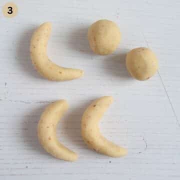 two dough balls and two shaped vanillekipferl on the table.