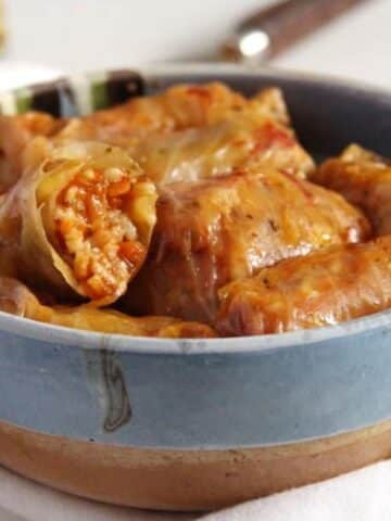 rustic bowl with many small vegan cabbage rolls with sauerkraut.