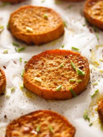 many baked sweet potato slices sprinkled with pepper and chives.