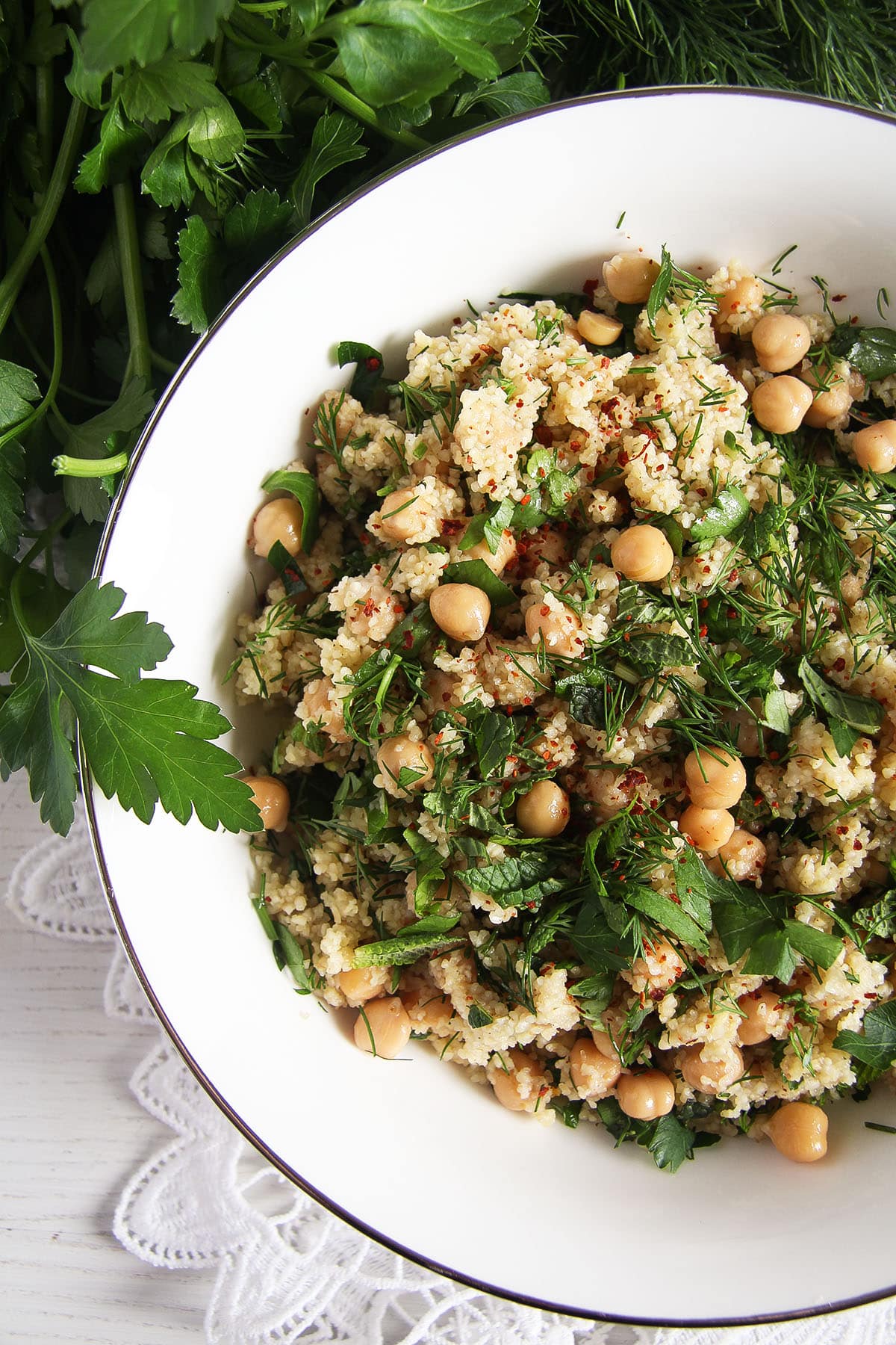 image showing half a white bowl full of bulgur salad with chickpeas and herbs.