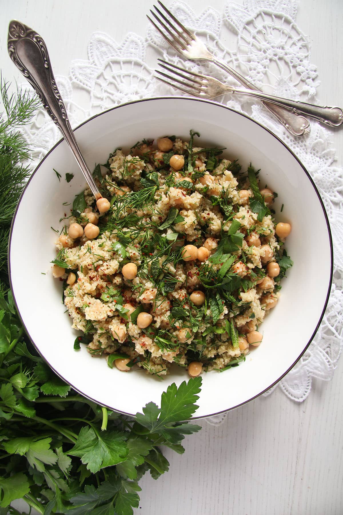 bulgur wheat salad with chickpeas and herbs in a bowl with a spoon sticking into it.