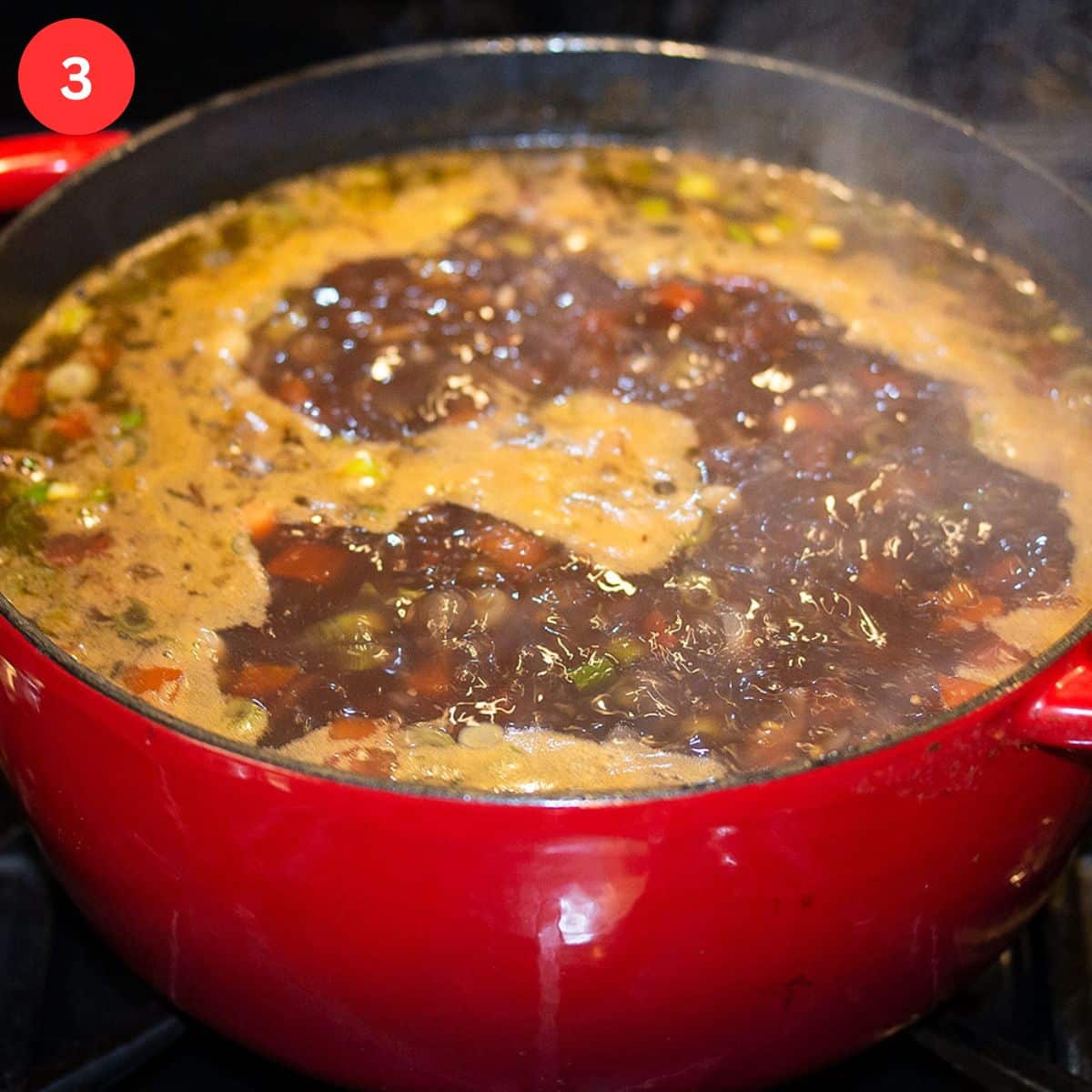 simmering pot of soup with lentils, vegetables and pasta.