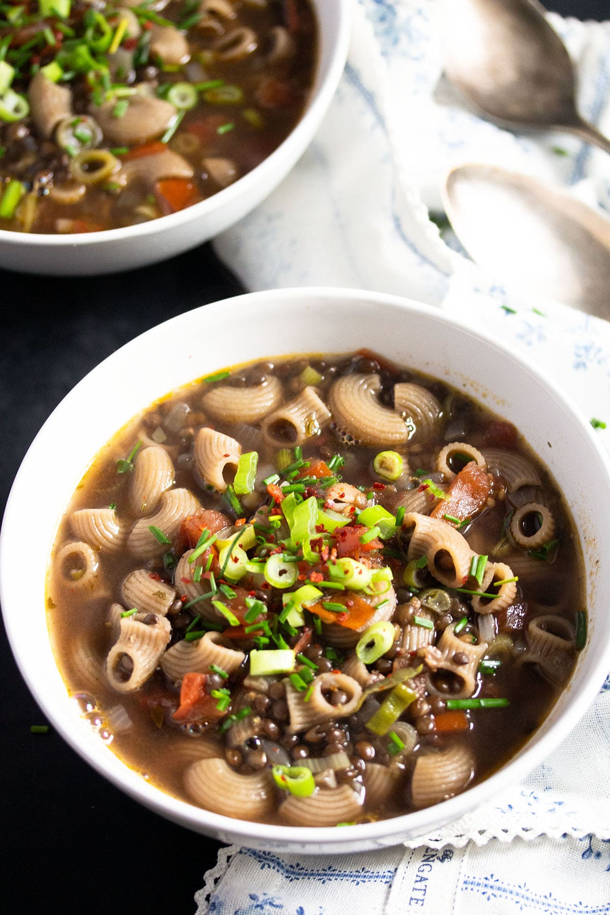 bowl of vegan beluga lentil soup with pasta, vegetables and herbs.