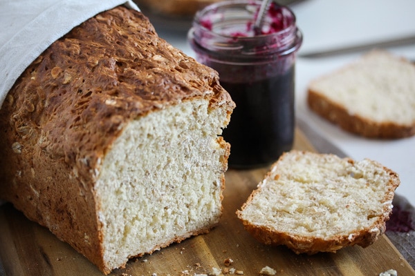 sliced oat bread without yeast with a jar of jam behind.