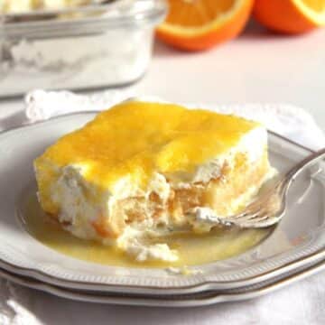 a slice of creamy orange tiramisu topped with orange sauce on a plate with a fork.