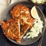 pancake-battered chicken served with lemon wedges and salad on a plate