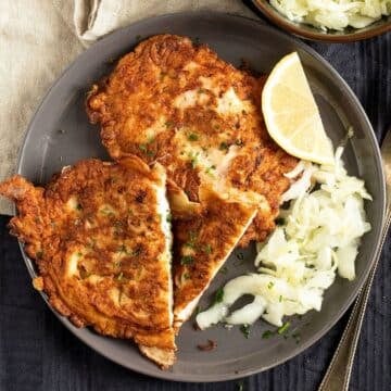 pancake-battered chicken served with lemon wedges and salad on a plate