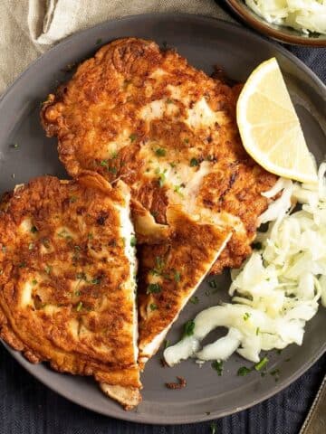 pancake-battered chicken served with lemon wedges and salad on a plate