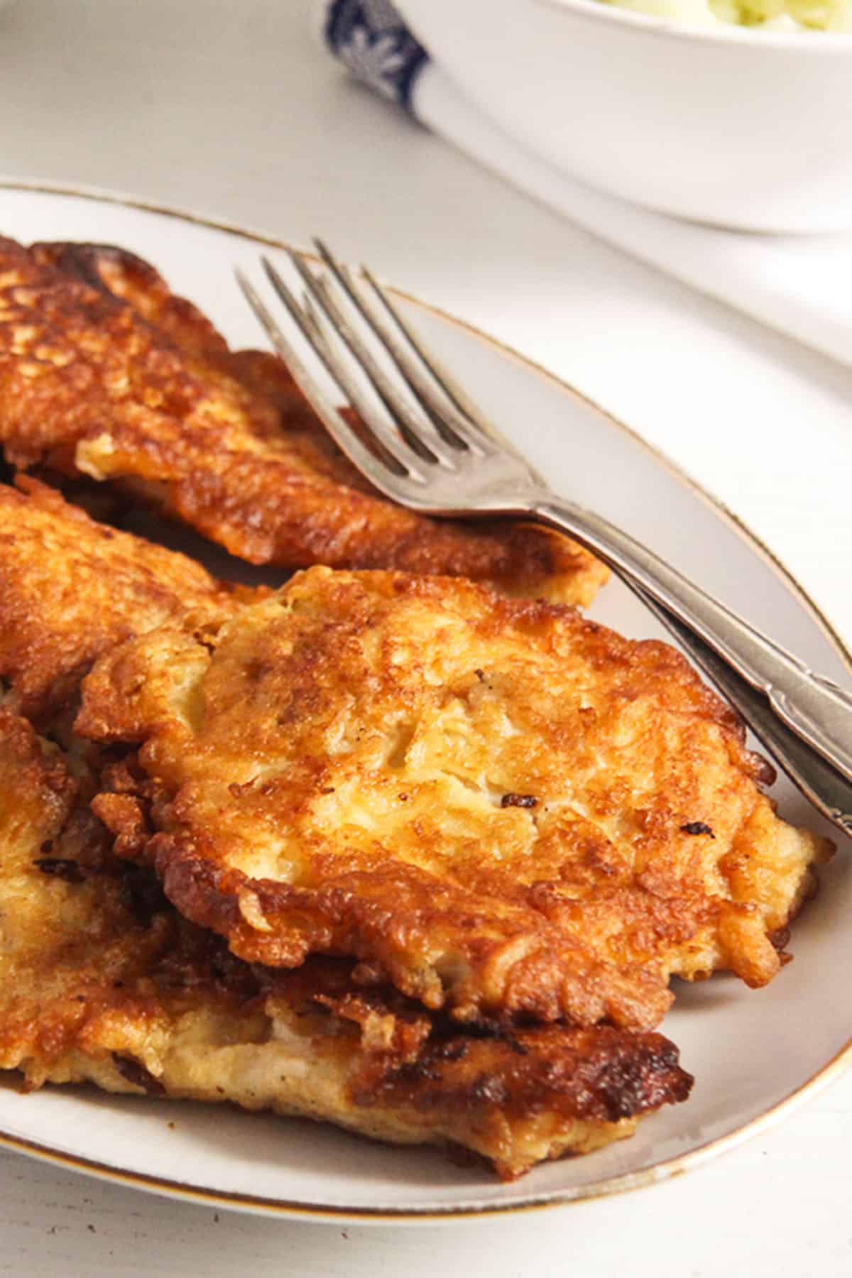 golden chicken breasts in pancake batter on a plate. 
