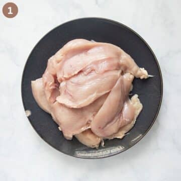 thinly sliced raw chicken pieces on a plate.