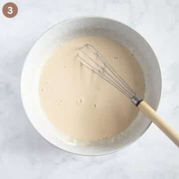 whisking pancake batter for chicken breast with a whisk in a large bowl.