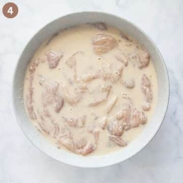 chicken breast pieces in pancake batter in a large bowl before cooking.