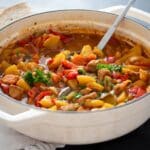 pork and potato stew in a large dutch oven with a serving laddle in it.