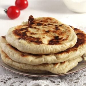 three romanian cheese pies or placinte cu branza on a plate and small tomatoes in the back.