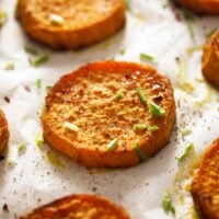 baked sweet potato rounds on a baking sheet lined with white parchment paper.