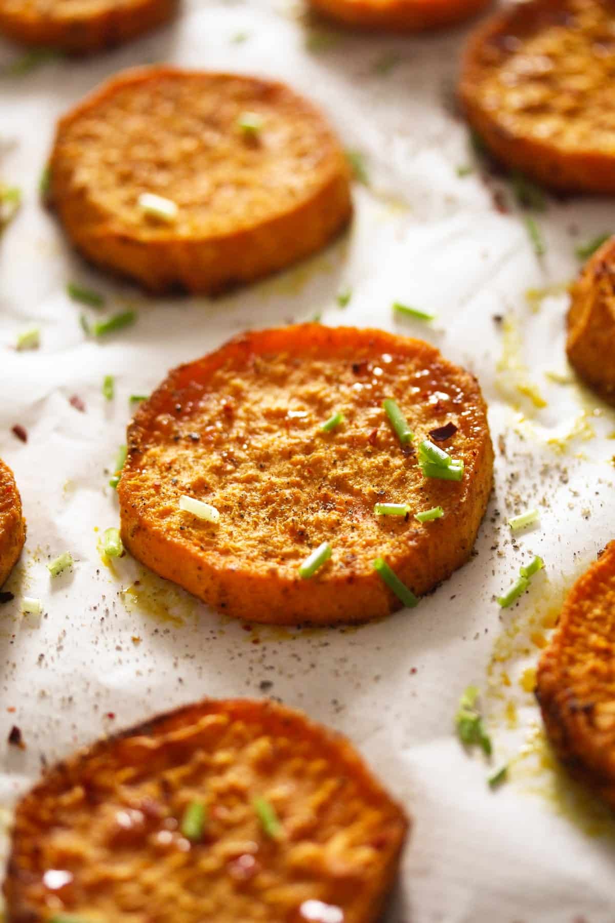 baked sweet potato rounds on a baking sheet lined with white parchment paper.
