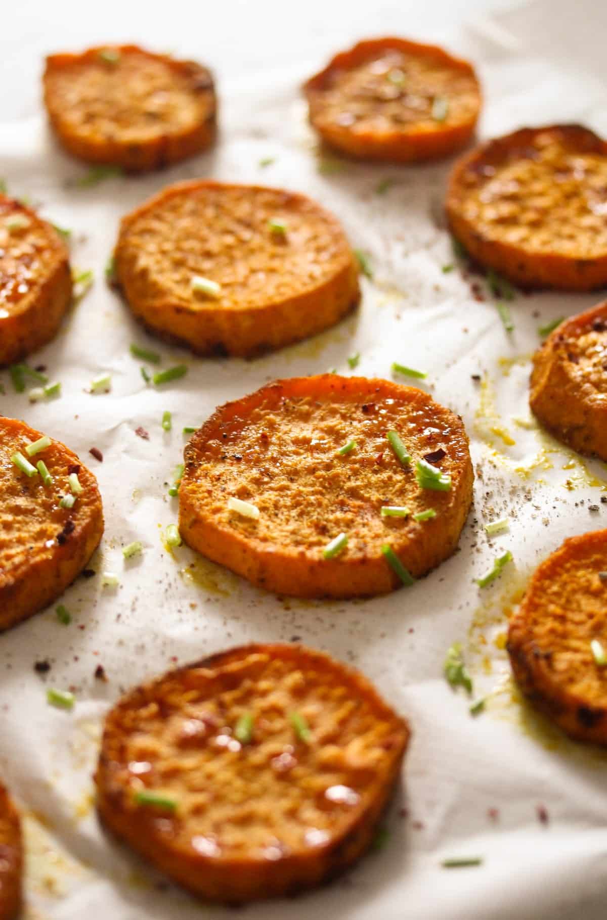 many roasted slices of sweet potatoes sprinkled with chives.