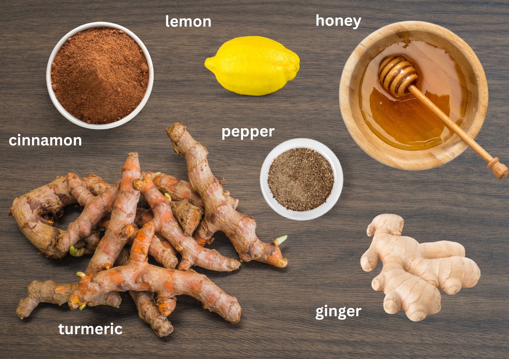 labeled ingredients for making turmeric tea with ginger, cinnamon, lemon, pepper, and honey.
